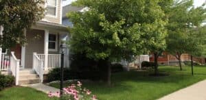 A Greenway dumpster outside a residential house with a tree.
