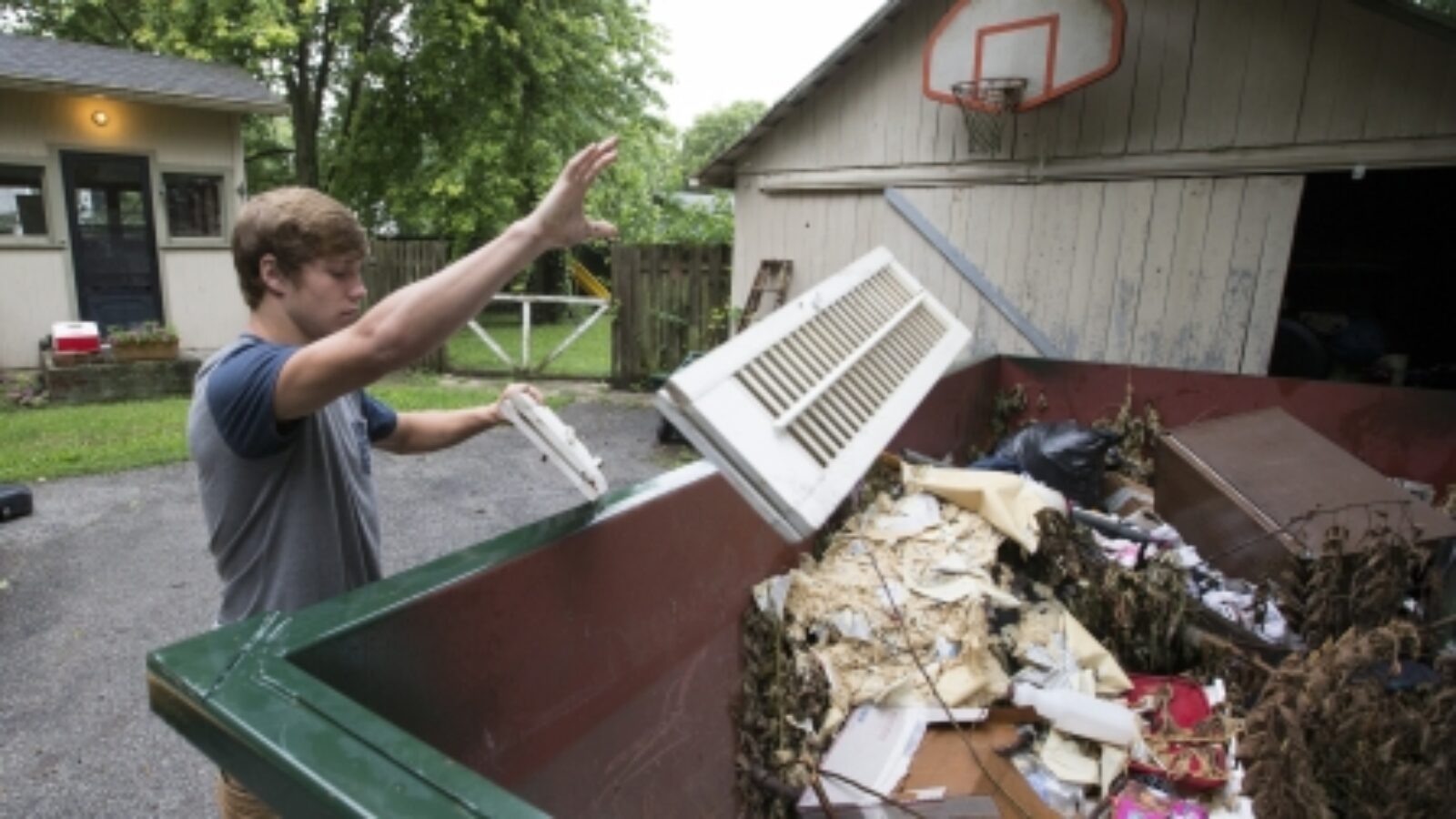 People throwing trash into a Greenway dumpster.