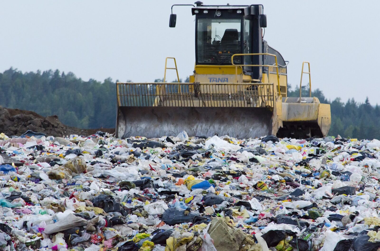 A bulldozer pushing trash at a landfill.