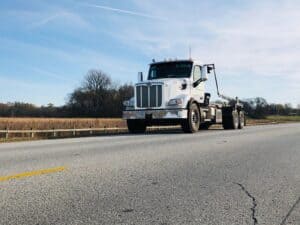 A high-definition image of a Greenway dumpster truck on a road