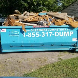 A Greenway dumpster angled sideways, overflowing with debris, and showing the contact number