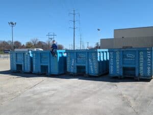 Jordan's son sitting on a dumpster with a collection of dumpsters in the background